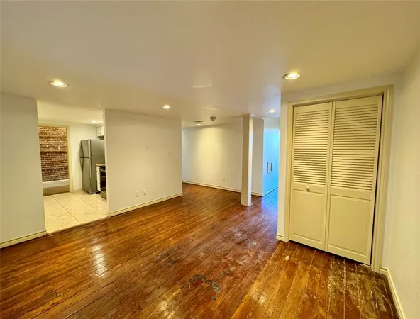a view of a big room with wooden floor and a kitchen