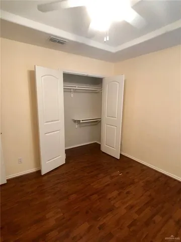 a view of an empty room with closet and wooden floor