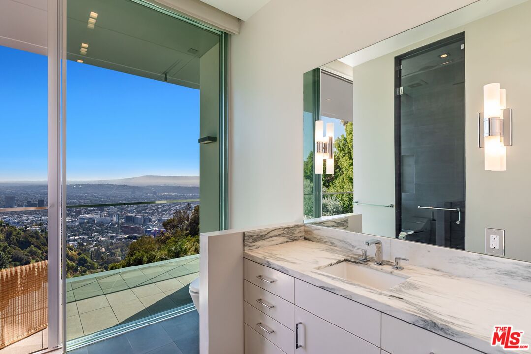 1895 Rising Glen Road Los Angeles, CA 90069 - Photo 17 of 41 a bathroom with a granite countertop sink and a large mirror