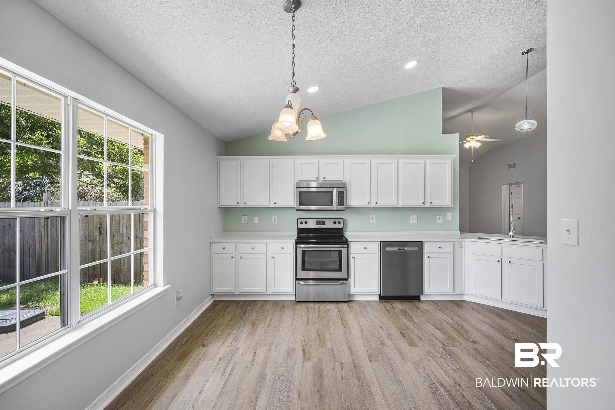 9814 Woolrich Avenue Fairhope, AL 36532 - Photo 5 of 29 Kitchen with appliances with stainless steel finishes, white cabinets, light hardwood / wood-style floors, and decorative light fixtures