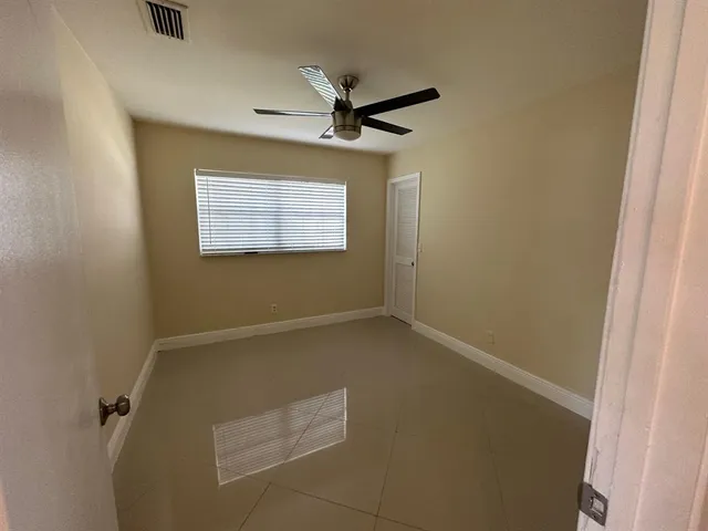 an empty room with a ceiling fan and a window