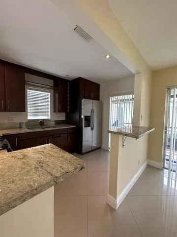 a kitchen with granite countertop a refrigerator and a stove top oven