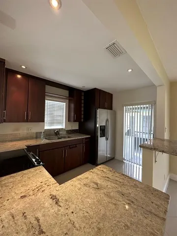 a large kitchen with kitchen island granite countertop wooden floors granite top and stainless steel appliances