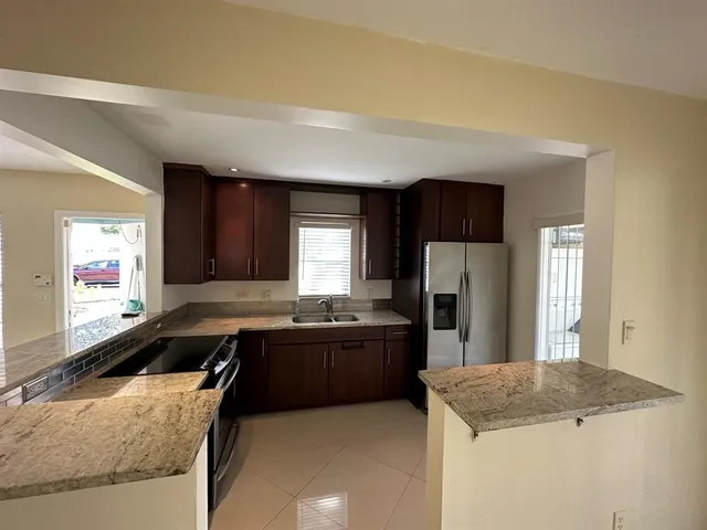 a kitchen with granite countertop a sink a stove and refrigerator