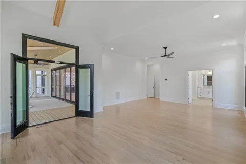 an empty room with wooden floor chandelier fan and windows