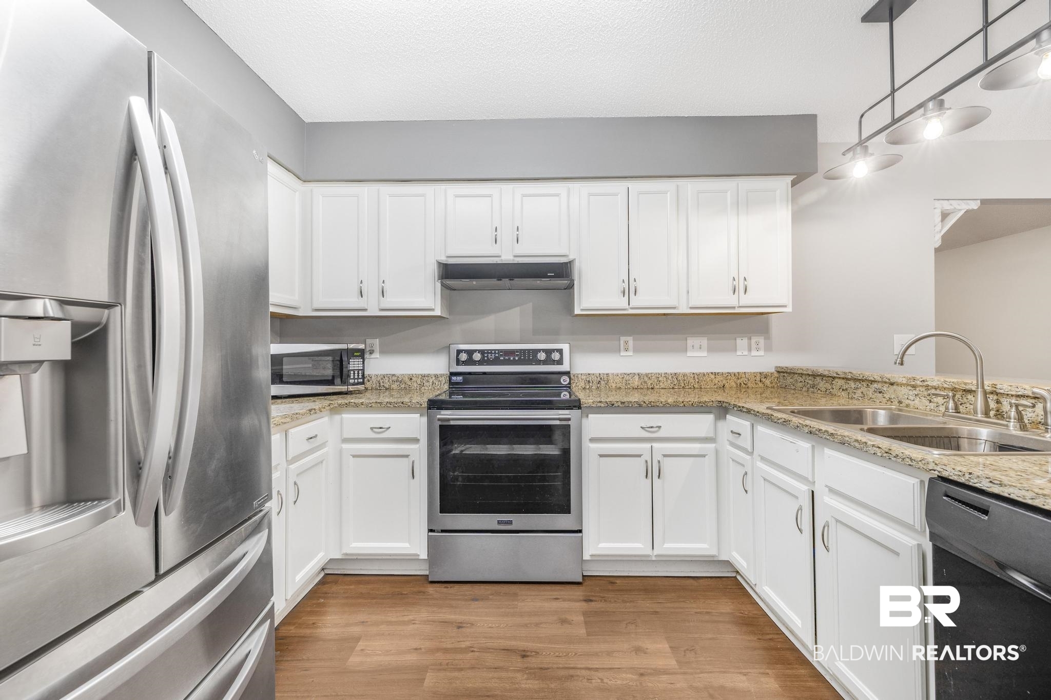 140 Hope Drive Daphne, AL 36526 - Photo 39 of 54 Kitchen featuring stainless steel appliances, light wood-style flooring, white cabinets, a textured ceiling, and light stone counters