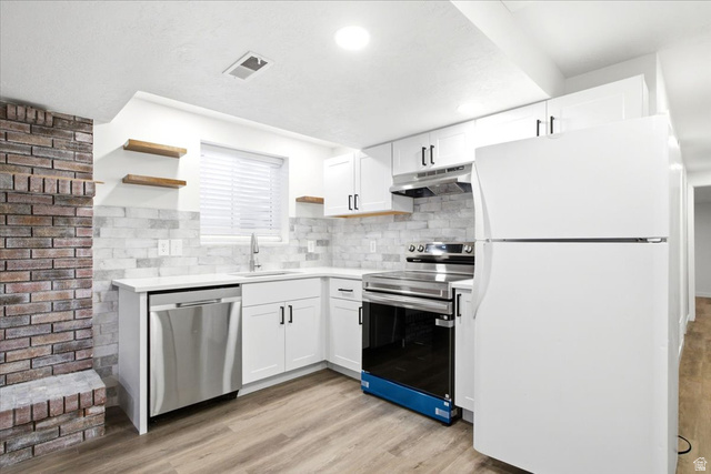1676 East 11245 South Sandy, UT 84092 - Photo 20 of 34 Bright basement kitchen featuring white cabinetry, a white countertop, a tile backsplash, and stainless steel appliances