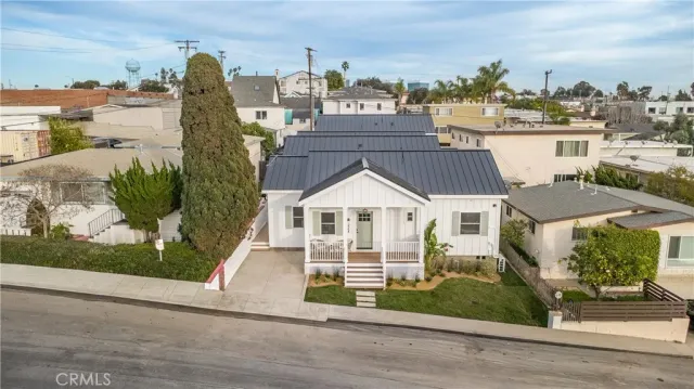 a view of a white house next to a yard with big trees