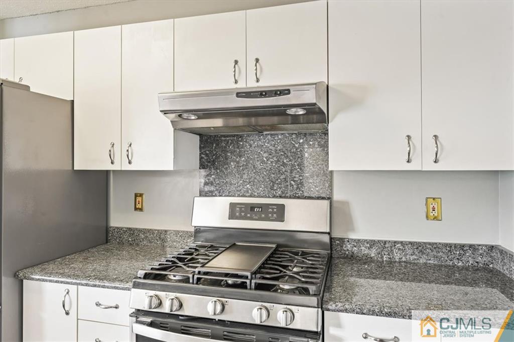 834 Edpas Road, Unit 834 New Brunswick, NJ 08901 - Photo 8 of 20 a kitchen with granite countertop a stove and a white cabinets