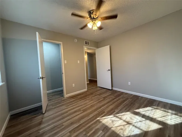 an empty room with wooden floor and a ceiling fan
