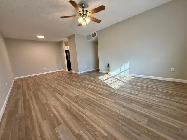 a view of a livingroom with a chandelier fan and wooden floor