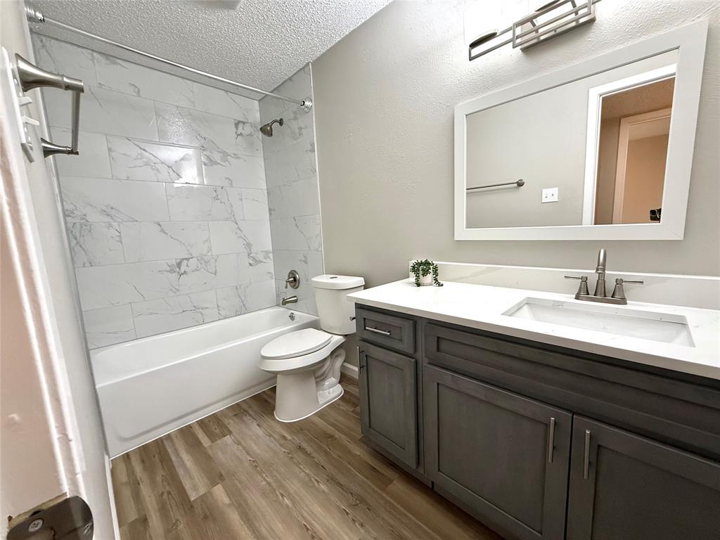 629 Central Avenue, Unit 202 Newark, TX 76071 - Photo 10 of 19 a bathroom with a sink a toilet a mirror a bathtub and shower