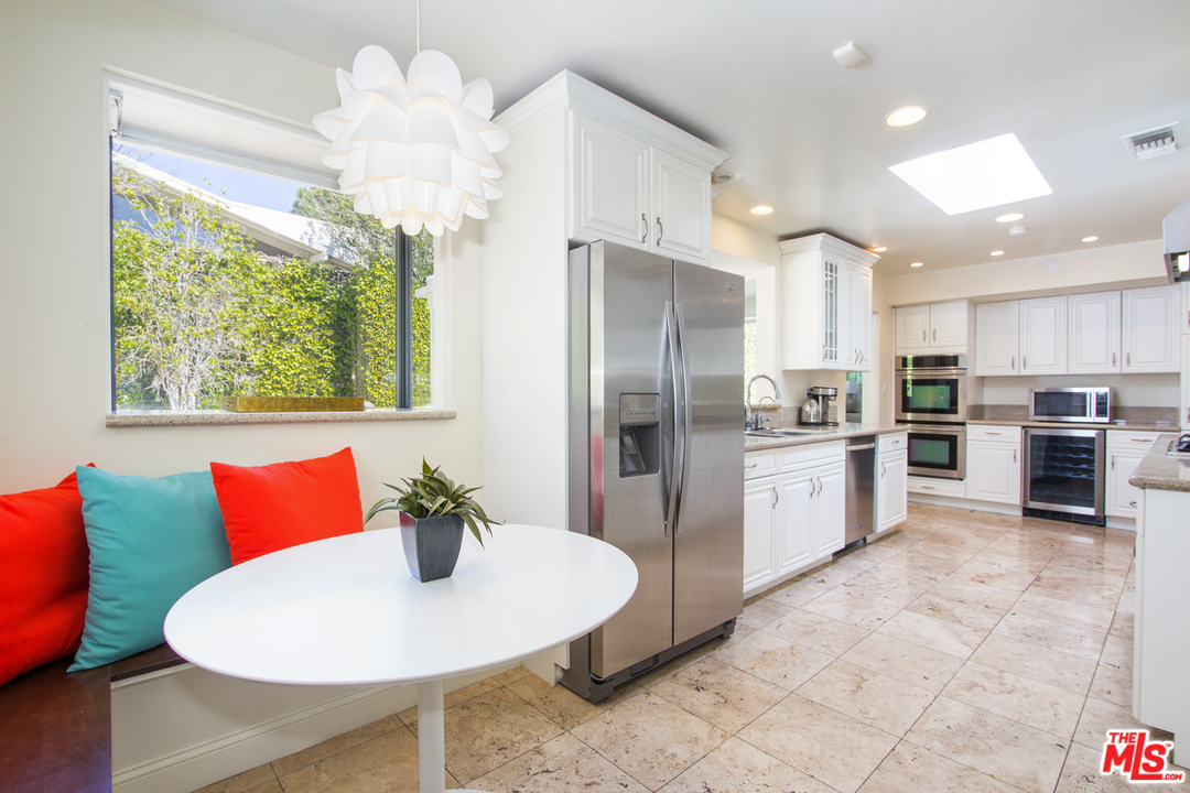 2267 Roscomare Road Los Angeles, CA 90077 - Photo 5 of 31 a kitchen with stainless steel appliances kitchen island granite countertop a refrigerator a sink a stove a dining table and chairs