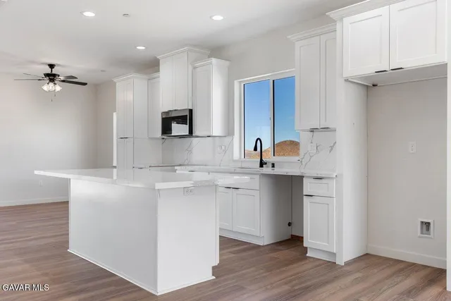 a kitchen with stainless steel appliances granite countertop a sink a stove a refrigerator and island with wooden floor