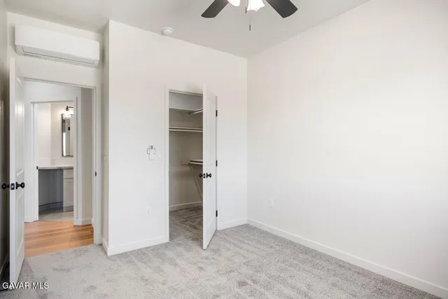 an empty room with a bathroom and a chandelier fan