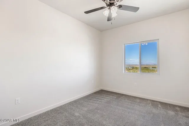 an empty room with a window and a ceiling fan