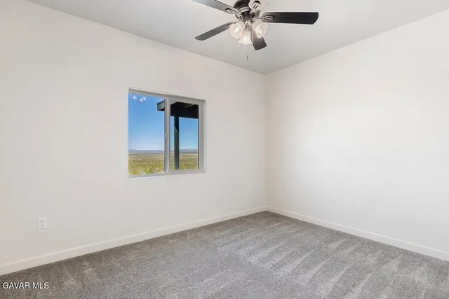 an empty room with a window and a fan