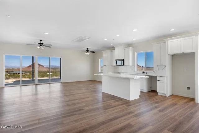 a view of kitchen with granite countertop refrigerator oven cabinets and wooden floor