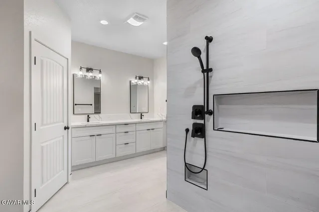 a bathroom with a granite countertop sink a mirror and a shower