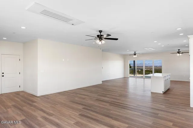 an empty room with wooden floor and ceiling fan