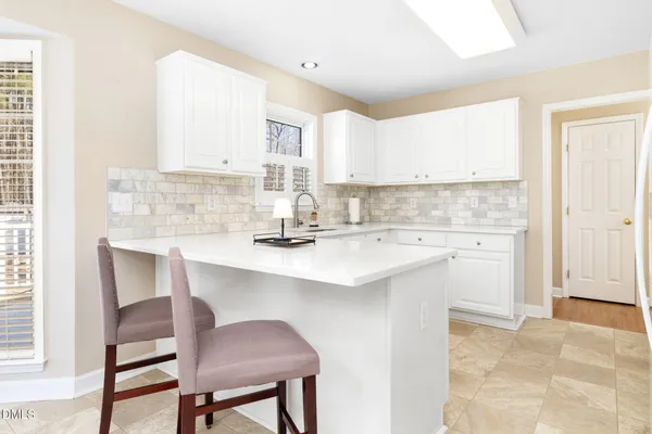 a kitchen with granite countertop a stove a sink dishwasher a dining table and chairs with wooden floor