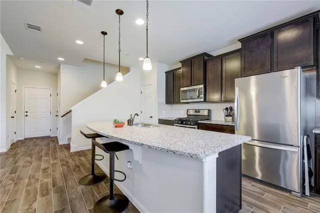 a kitchen with a sink a center island stainless steel appliances and cabinets