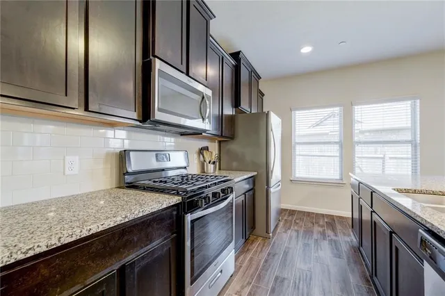 a kitchen with stainless steel appliances granite countertop a stove a sink and a refrigerator