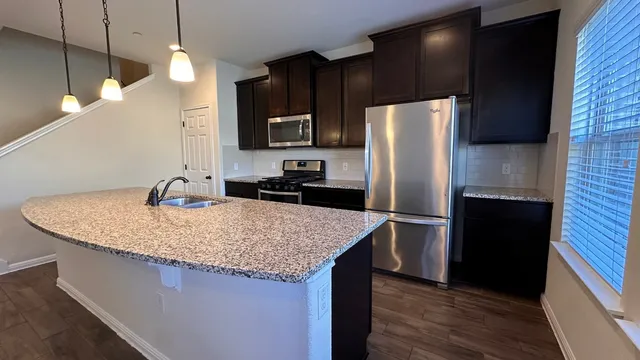 a kitchen with stainless steel appliances granite countertop a sink refrigerator and microwave