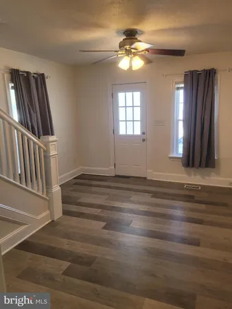an empty room with wooden floor fan and windows