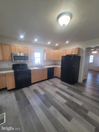 a kitchen with stainless steel appliances kitchen island granite countertop a refrigerator and a stove top oven