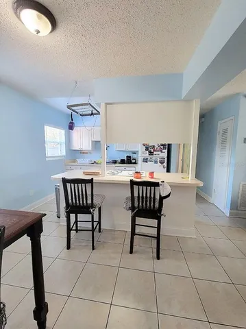 a dining room filled a chandelier and kitchen view