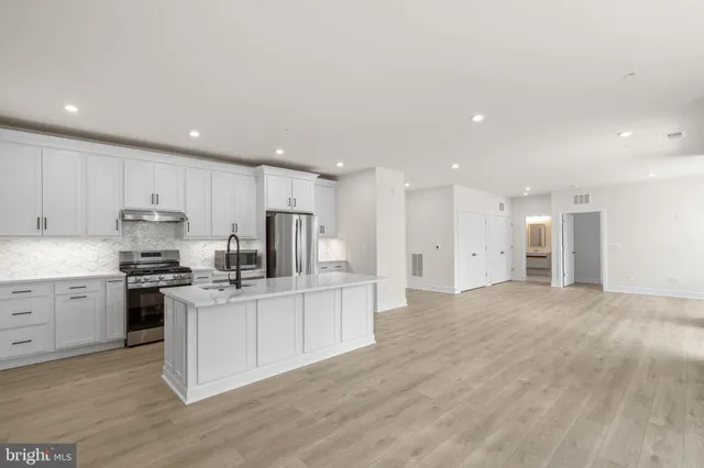 a kitchen with stainless steel appliances granite countertop a stove top oven a sink and a refrigerator