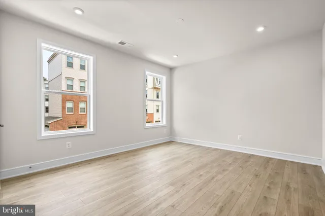 an empty room with wooden floor and windows