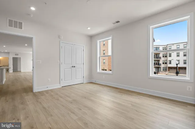 a view of an empty room with window and wooden floor