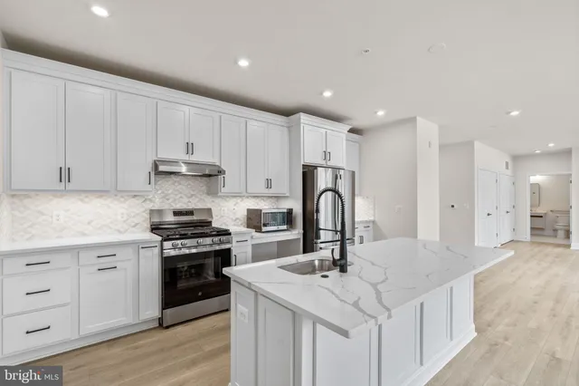 a kitchen with a sink a stove a refrigerator and white cabinets