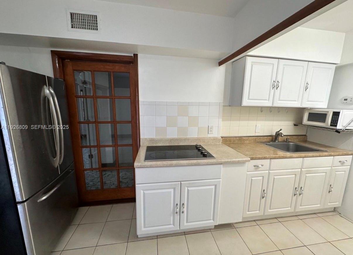 3894 Northwest 5th Street, Unit 3 Miami, FL 33126 - Photo 5 of 10 a kitchen with white cabinets and a refrigerator