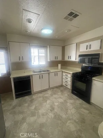 a kitchen with granite countertop a stove a sink and a refrigerator