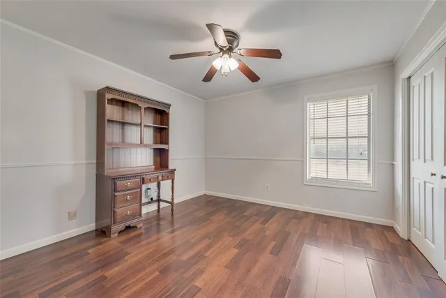 an empty room with wooden floor chandelier fan and windows