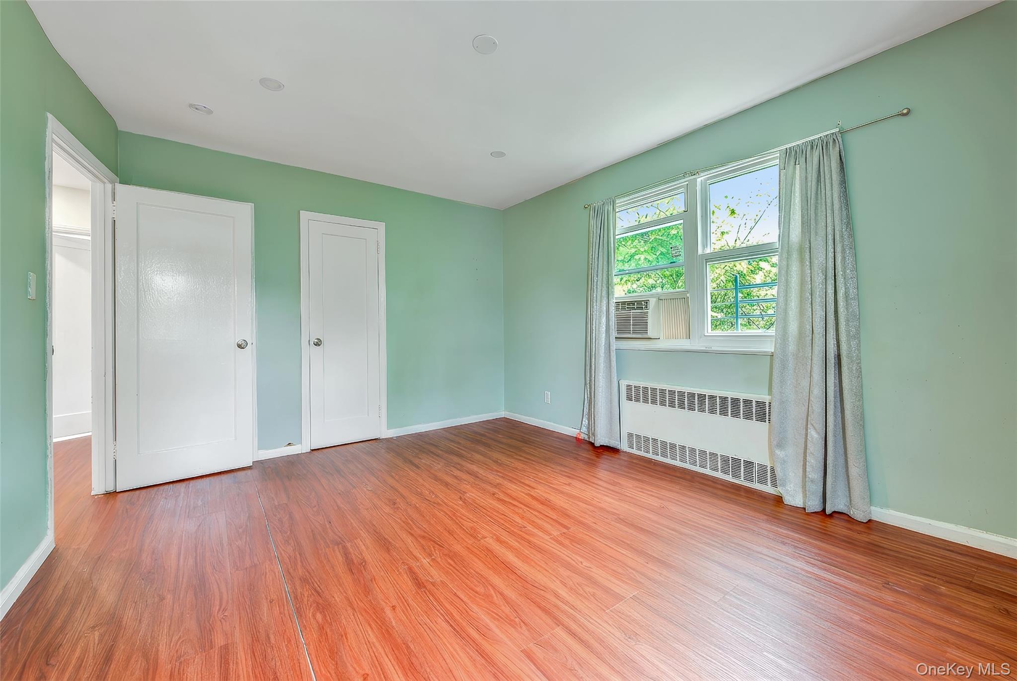164-38 76th Road Queens, NY 11366 - Photo 18 of 44 a view of an empty room with wooden floor and a window