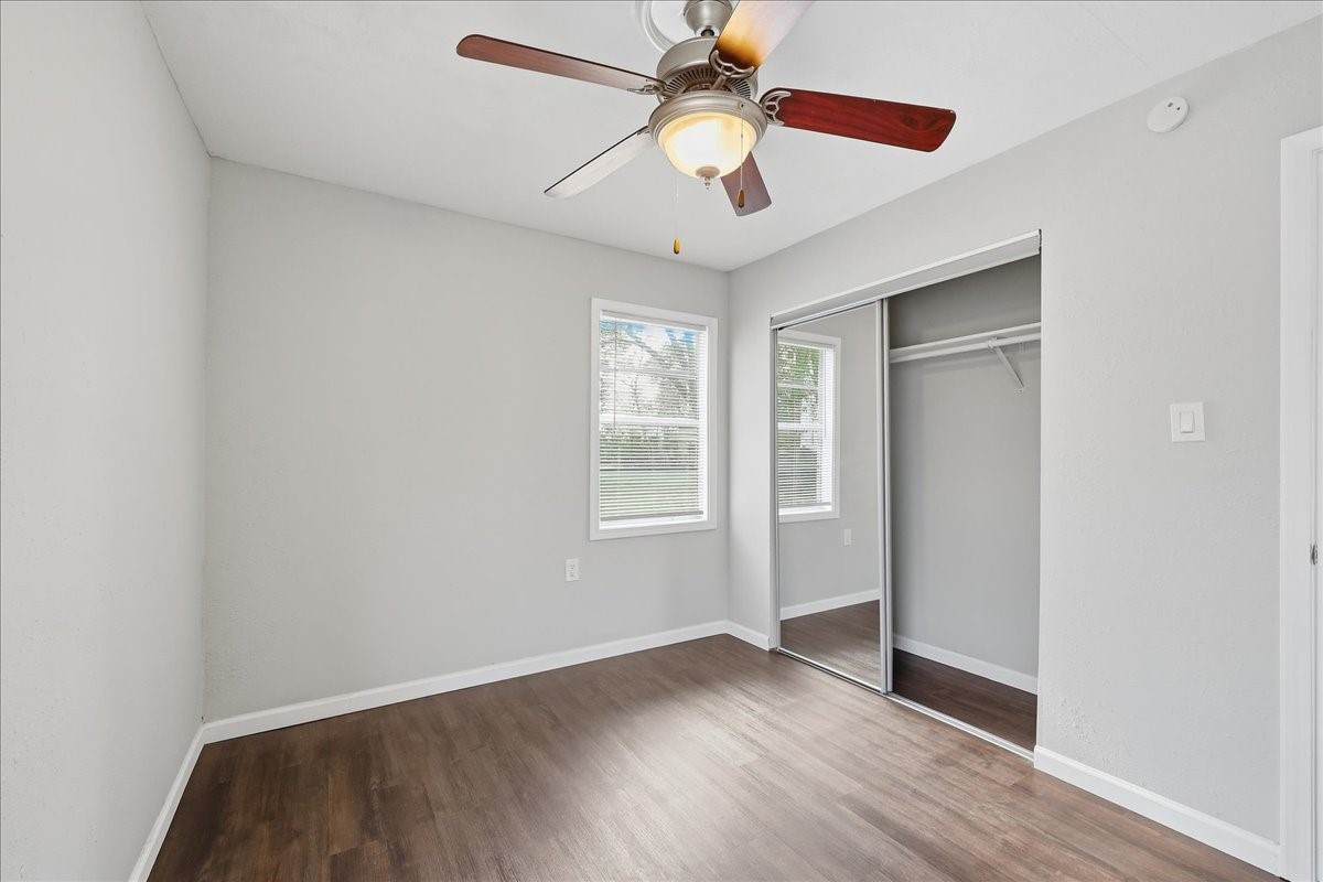 1415 Beagle Road Orange, TX 77632 - Photo 18 of 23 an empty room with wooden floor chandelier fan and windows