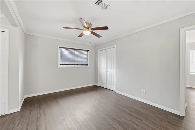 a view of empty room with wooden floor and fan
