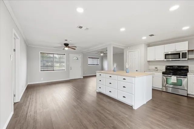 a kitchen with wooden floors and white cabinets