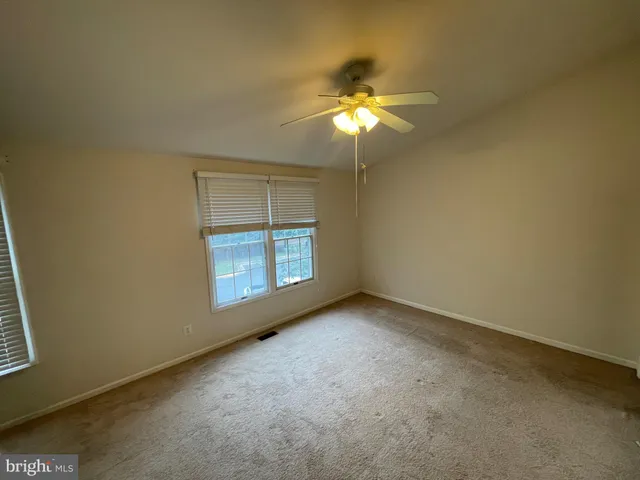 an empty room with a window and chandelier fan
