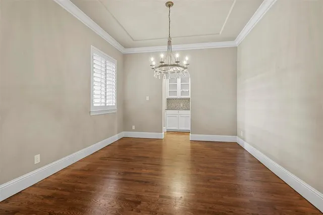 an empty room with wooden floor chandelier and windows