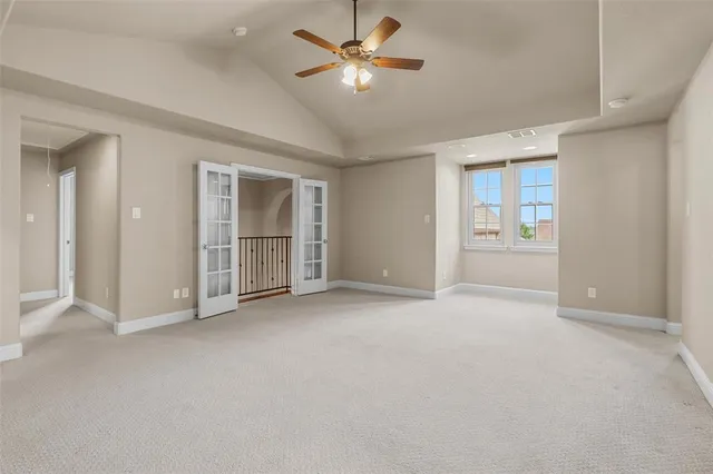 an empty room with chandelier fan and windows