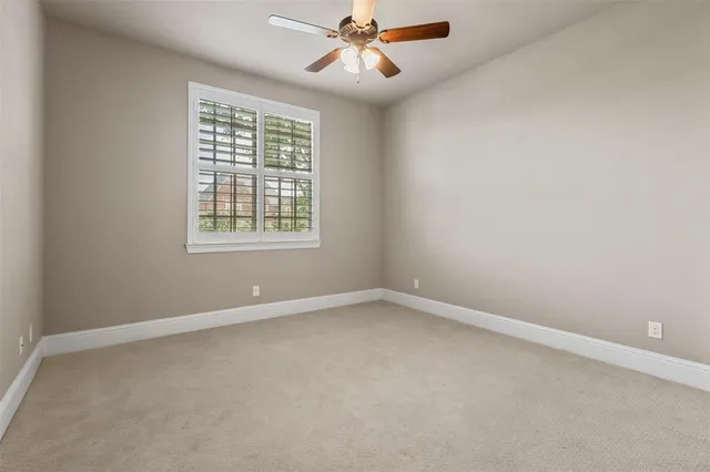 an empty room with chandelier fan and windows