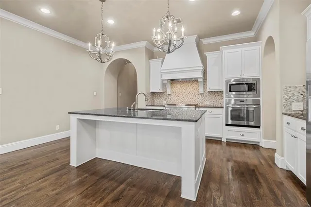a view of a kitchen with granite countertop wooden floor a refrigerator and a sink