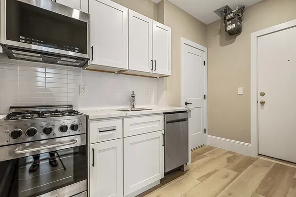 a kitchen with stainless steel appliances white cabinets and a stove top oven