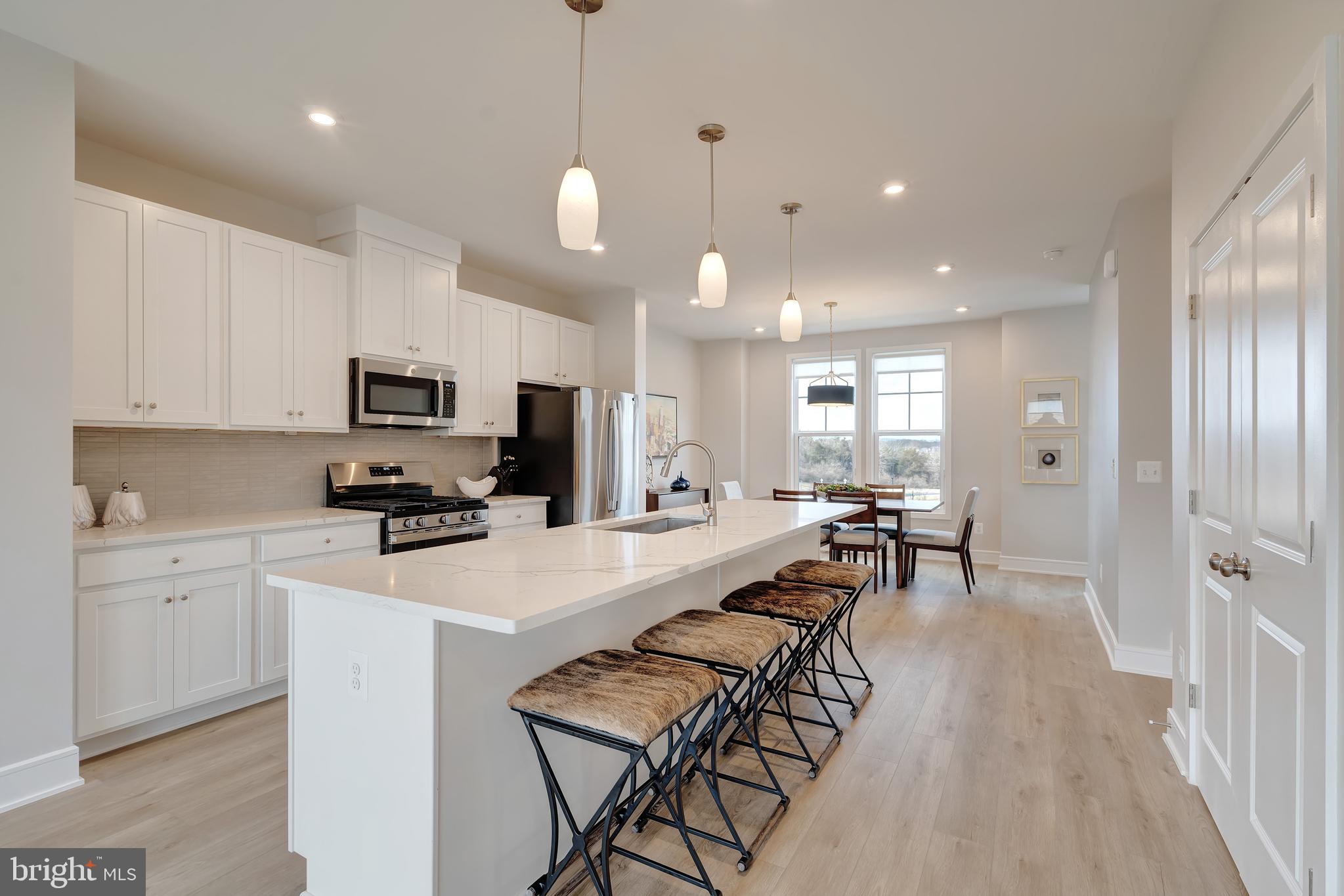 105 Checkerspot Way White Post, VA 22663 - Photo 14 of 37 a kitchen with stainless steel appliances kitchen island granite countertop a stove a sink a dining table and chairs with wooden floor