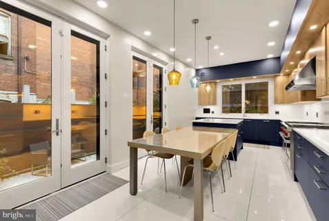 a kitchen with stainless steel appliances kitchen island granite countertop a stove a refrigerator a dining table and chairs with wooden floor